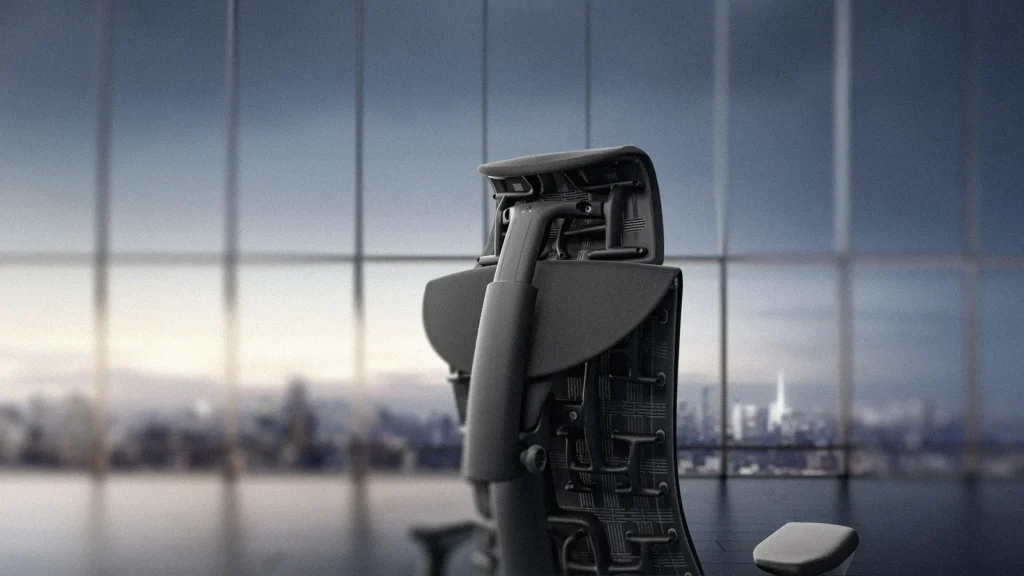 Close-up van een moderne bureaustoel met een rugleuning van mesh en een ergonomisch ontwerp, in een kantoor met een grote raamwand met uitzicht op een wazig stadsgezicht.