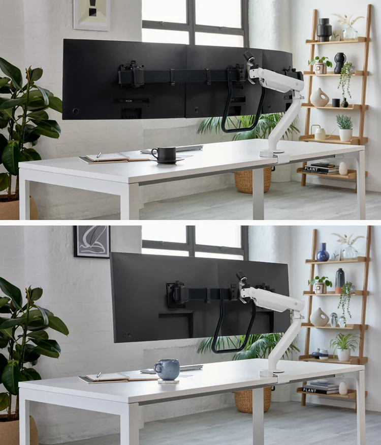 Een minimalistische thuiskantooropstelling heeft een grote gebogen monitor op een witte Herman Miller Flo X verstelbare arm. De strakke Herman Miller stoel, mok, notitieboekje en pen verbeteren de functionaliteit. Op de achtergrond maken potplanten, een ingelijste foto en een houten plank met decoratie het tafereel compleet.