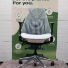 Een moderne ergonomische bureaustoel met een netrugleuning en een zachte zitting staat voor een groene banner die duurzaam ontwerp promoot, met pictogrammen en tekst over de milieuvriendelijke eigenschappen en duurzame kwaliteit.